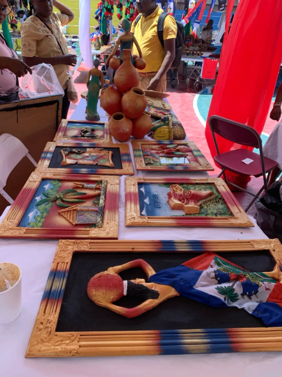 Colorful framed artisan artwork displayed at a Haitian market.