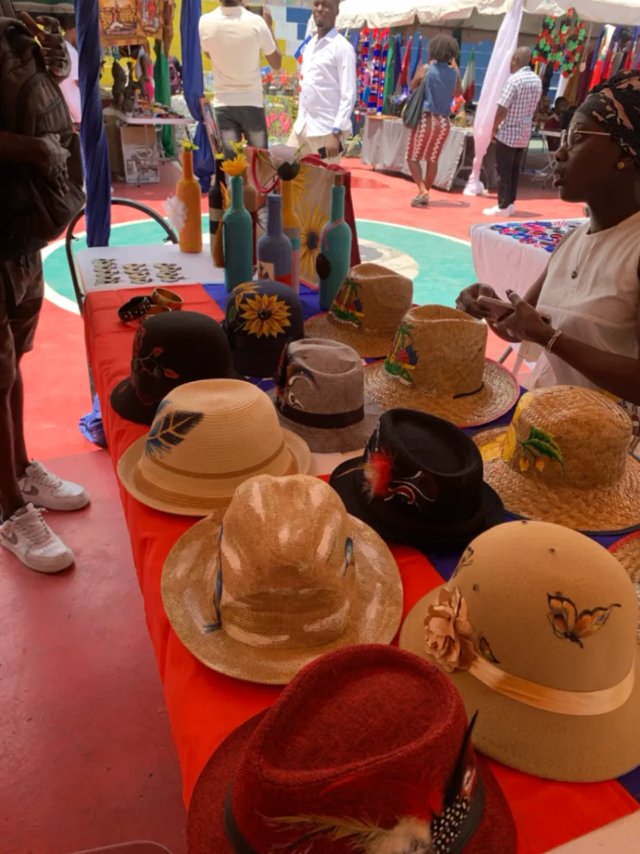 A market table displaying handwoven straw hats and colorful artisan goods.